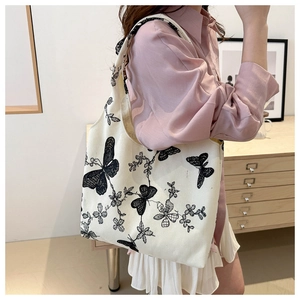 Detailed close-up of cream canvas hobo bag with black butterfly and floral prints