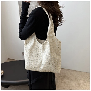 Detail of cream hollow-out embroidery fabric on a lightweight minimalist hobo tote bag