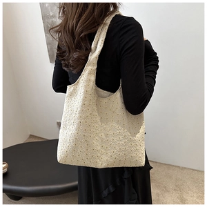 Detail of cream lace crochet tote bag featuring intricate floral hollow embroidery patterns