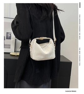 Detail of white crinkle leather shoulder bag with gold hardware worn by model