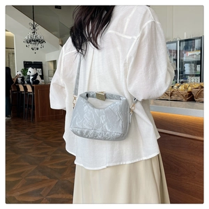 Close-up of light blue pleated PU leather crossbody bag with elegant gold metal lock