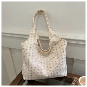 Detailed view of floral embroidery on cream canvas tote bag with elegant lace texture