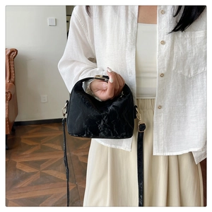 Detail of black pleated PU leather texture on hand-held crossbody bag with adjustable strap