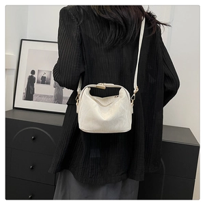 Detail of white pleated dumpling bag with gold clasp and slim strap on shoulder