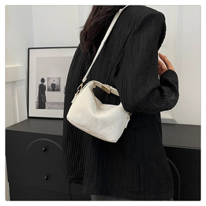 Detail of white crescent bag with pleated texture and golden metal buckle clasp