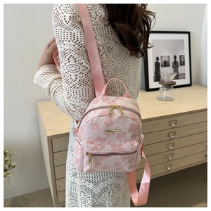 Detailed view of pink floral jacquard backpack with zip pockets on a female model