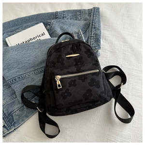 Macro detail of black mini backpack with elegant 3D floral texture and gold hardware