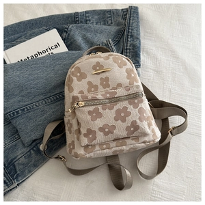 Detail of floral embroidery on a cream-colored mini backpack with golden metal accents