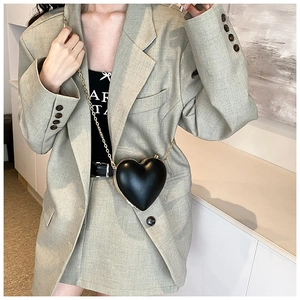 Dettaglio di una borsa a tracolla nera a forma di cuore con elegante catena dorata