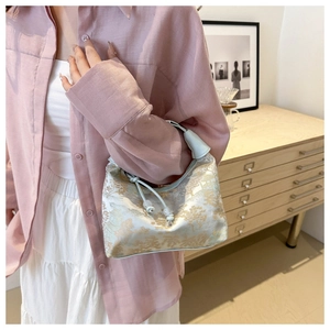 Detail of light blue jacquard bucket bag with golden embroidery and drawstring closure