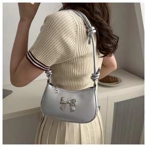Detail of silver leather shoulder bag featuring a metallic bow and knotted rope strap