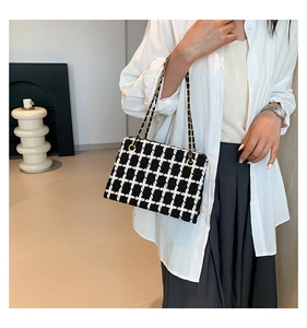 Close-up of black and white tweed plaid texture with golden metal chain strap details