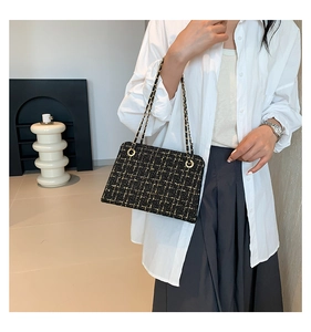 Detail of tweed crossbody bag with black gold woven texture and leather chain strap