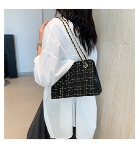 Detail of tweed shoulder bag with gold chain strap worn over a white shirt and black skirt