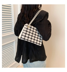 Detail view of the black and white plaid tweed chain bag worn on a shoulder