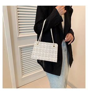 Detailed view of beige tweed chain bag with gold stitching and metallic strap