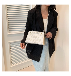 Detail of tweed crossbody bag in cream with gold chain strap on model in black blazer