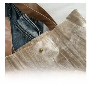 Close-up of champagne velvet tote bag with magnetic clasp and brown leather handles