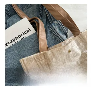 Detail of champagne tote bag showing brown leather handles and gold metal rivets