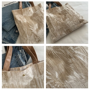 Close-up of velvet tote bag featuring golden leaf patterns and magnetic snap button