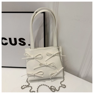 Detail of white leather bucket bag with bow accents and silver beaded chain strap
