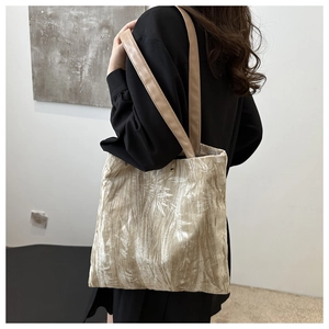 Detail of velvet bamboo embroidered tote bag with pleated texture and leather handles