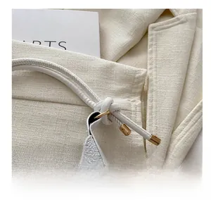 Macro shot of off-white lychee textured leather bag with gold hardware and knotted strap