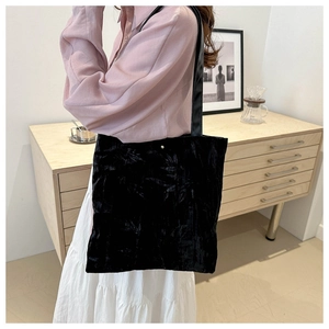 Close-up of pleated black velvet texture and leather straps on large tote bag