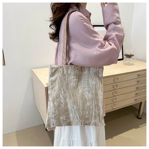 Elegant bamboo leaf embroidered velvet tote bag worn by a model in a modern home setting