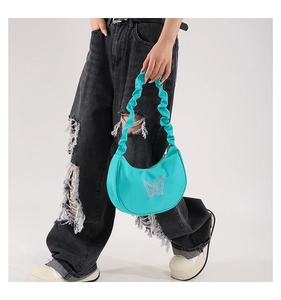 Detail of mint green half-moon bag featuring pink butterfly embroidery and ruffled strap