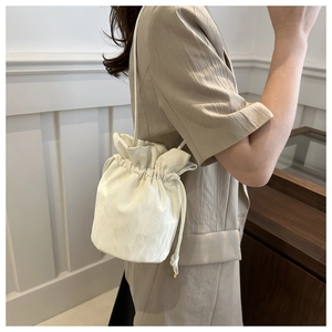 Close-up of cream drawstring bucket bag showing soft fabric texture and pleated detail