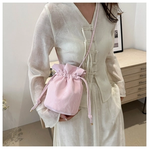 Pink drawstring bucket bag with gold hardware shown in a modern home interior setting