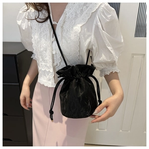 Detail of elegant black drawstring bucket bag in satin fabric on a shoulder strap