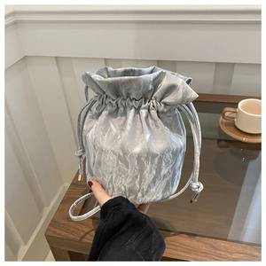 Detail of silver drawstring bucket bag showing metallic pleated texture and rope strap