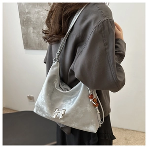 Borsa hobo in velluto argento con fiocco in metallo e ciondolo di perle su una modella