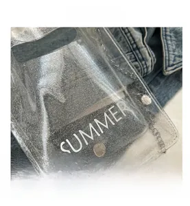 Detail of transparent PVC bag with silver sequins and Summer text on denim background