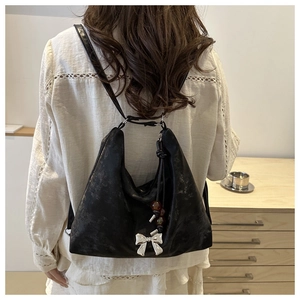 Borsa Hobo vintage nera con fiocco argento e perline indossata da modella in interni