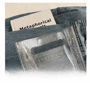 Detail of transparent PVC beach bag with silver sequins on blue denim background