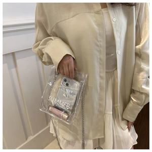 Close-up of clear PVC crossbody bag with silver chain strap and white SUMMER print