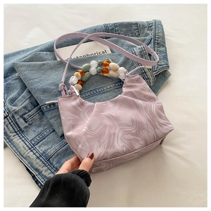 Détail du sac à main marbré violet clair avec poignée en perles acryliques et bandoulière