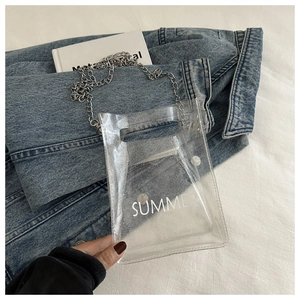Close-up of clear glitter PVC bag with silver chain and white SUMMER text on denim