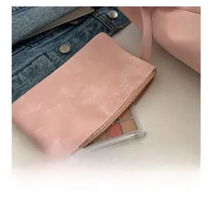 Detail of pink PU leather charm pouch with zipper showing compact interior storage