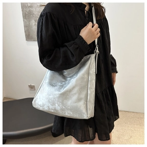 Dettaglio della borsa tote argento metallizzato con trama stropicciata portata a spalla