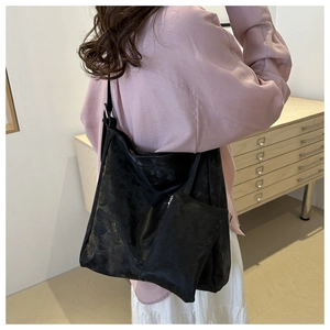 Detail of a large metallic black PU hobo bag with matching mini pouch on a female model