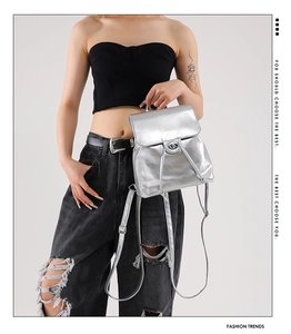 Detail of silver metallic mini backpack featuring a twist lock and drawstring closure
