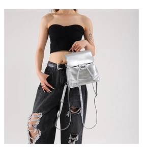 Detail of silver metallic mini backpack with laser finish and buckle closure shown on model