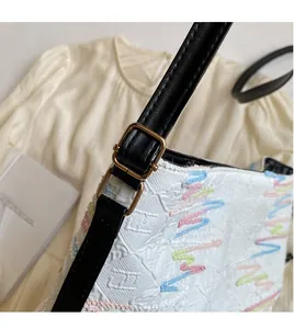 Détail du sac fourre-tout en jacquard blanc avec broderie colorée et bandoulière réglable noire