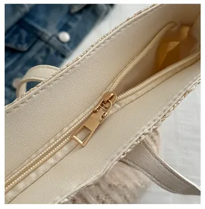Detail of smooth pale gold metal zipper and woven texture on beige tote bag