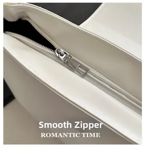 Detail view of smooth silver metal zipper on white pleated shoulder bag top opening