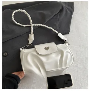Detailed view of white pleated cloud bag with silver heart buckle and braided strap